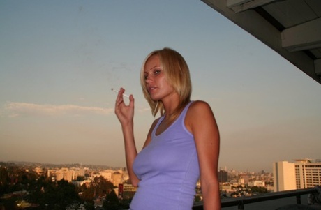 Blonde Chick Causally Displays No Panty Upskirt While Smoking On Condo Balcony