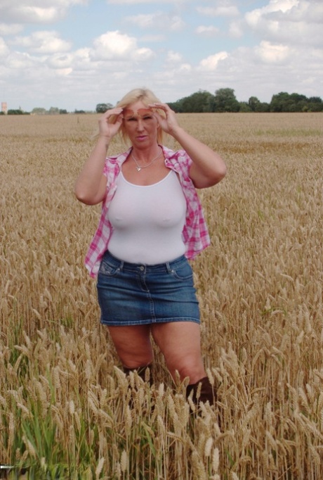 In a field environment, MILF Melody, a chubby mature female, displays great big tits and flashes a hot ass.