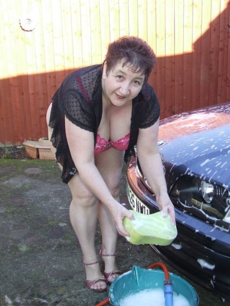 The car wash attractive woman, Kinky Carol, shows off her large tits while washing.