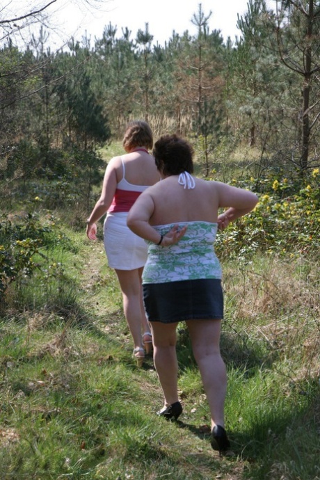 Old lady Kinky Carol and her partner stand near trees with their large tits.