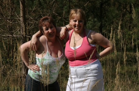 Older lady, Kinky Carol and her partner stand near trees with their big tits sticking out.