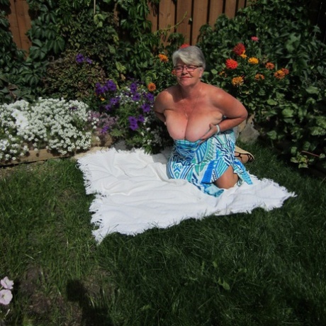 A fat nan Girdle Goddess undresses herself onto sheer pantyhose on a blanket by the flower bed.