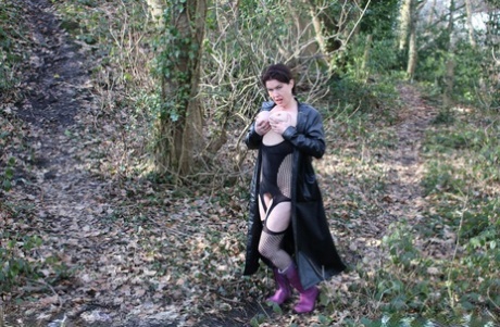 British adult female Juicey Janeyer displays her large breasts and vagina in the woods.