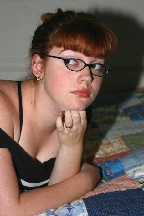 Chubby nerd with red hair removes her glasses after uncupping big naturals.