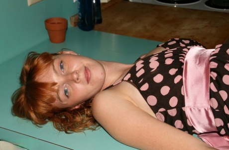 Using a polkadot dress, Marie Mc Cray, a natural redhead, exposes her naked body in the kitchen.