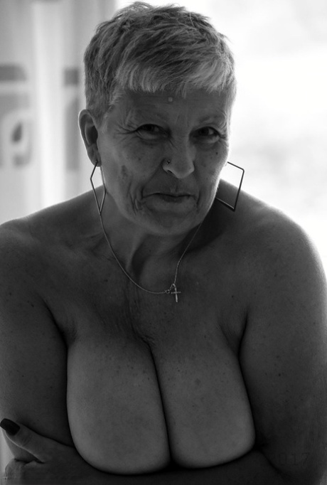 Wearing a fishnet pantyhose and strapped on, an elderly woman with short hair and floppy tits.