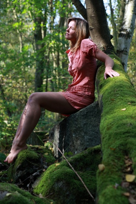 In a forest, young girl and her boyfriend engage in sexual activity on moss-covered boulders.
