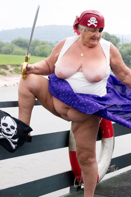 Fat British granny bares her legs on a bridge while dressed as a pirate and ready for action.