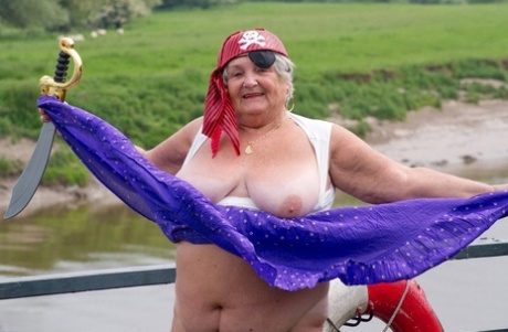 In the guise of a pirate, fat British granny flaunts her body on a bridge.