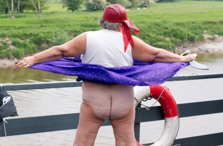 On a bridge, a fat British granny flaunts her chest in the siesta dressed as a pirate.