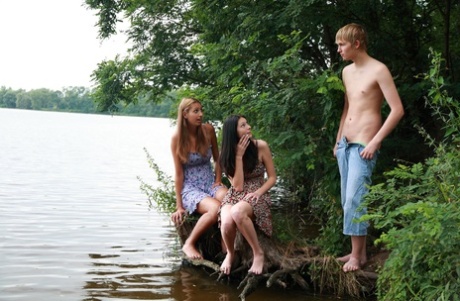 Two girls who identify as bisexual engage in a threesome with a boy in shallow lake water.