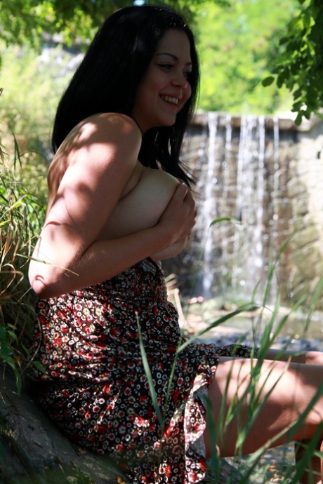 Katarina, the Latina girl with big tats on her hips, removes her clothing to nude on a riverbank.