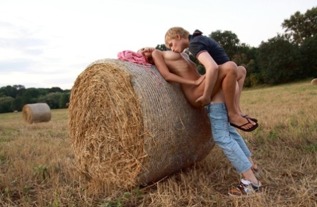 Young couple have sexual intercourse against a round bale in a farmer's field