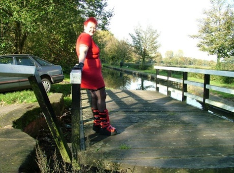 Punk boots: Mature redhead Valgasmic Exposed poses on a footbridge, her feet naked.