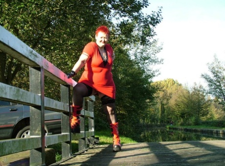 In a footbridge, Valgasmic Exposed exposes her red hair and wears punk boots.