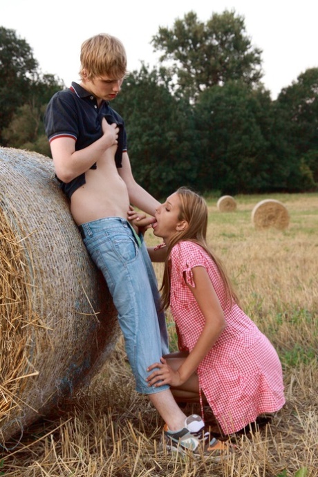The Horny young couple engage in sexual activity with a round bale while playing football in the middle of the field.