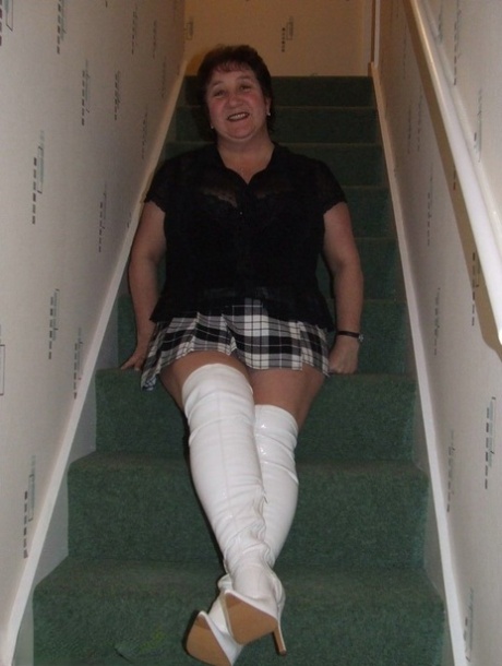 Mature BBW Kinky Carol gets naked in her underthings and OTK boots on stairs