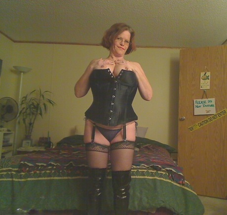 In OTK boots, Misha MILF, a redheaded amateur who is wearing one of the above images, looses her large tits from a corset.