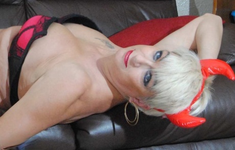 Mature platinum blonde Dimonty draws on a vaporizer while naked in OTK boots