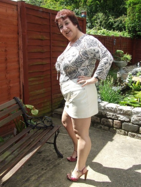 Mature BBW Kinky Carol shows her upskirt underwear on a patio in a bra