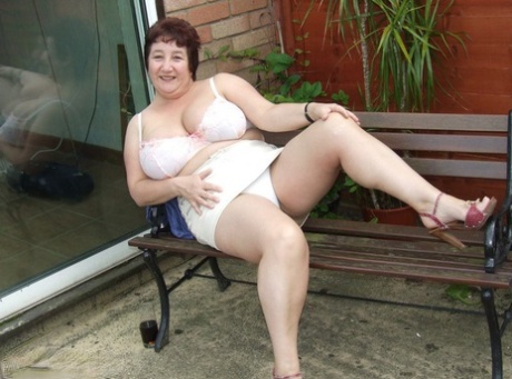 Mature BBW Kinky Carol shows her upskirt underwear on a patio in a bra