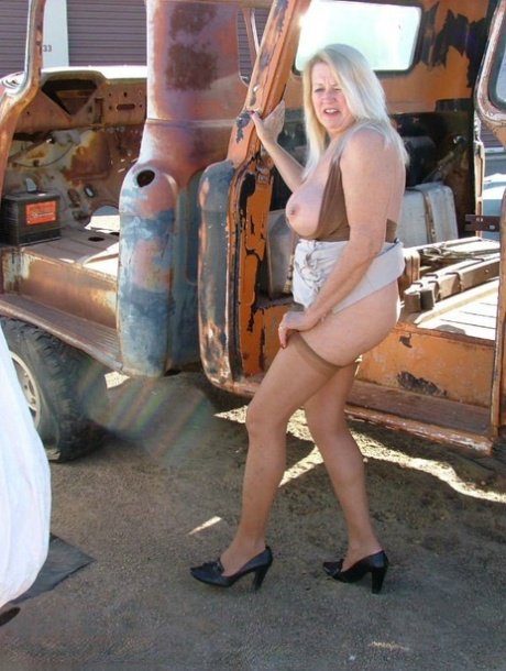 A mature blonde displays her ample tits and buttocks on heavy equipment that is stripped down.