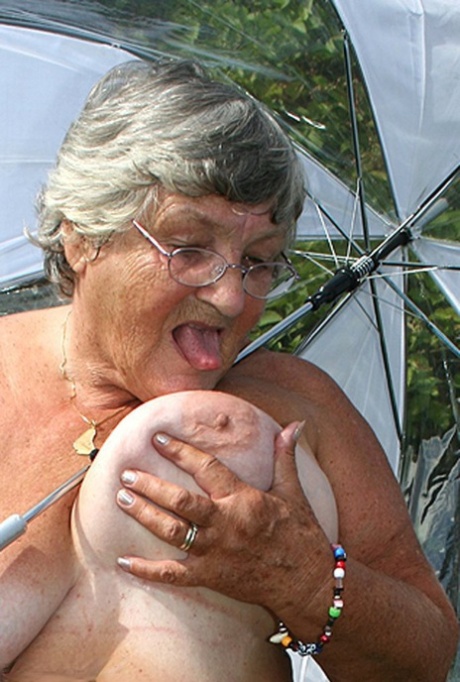 Obese Oma Grandma Libby Holds An Umbrella While Posing Naked By Fir Trees