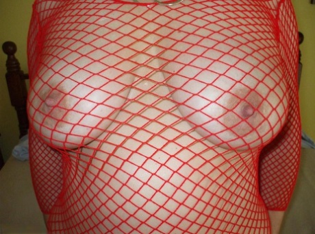 Older Woman Licks Her Lips While Posing By Herself In A Mesh Top