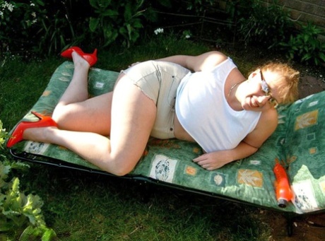 A UK amateur curlican named Claire shows off her boobs on a lawn chair while giving a dildo.