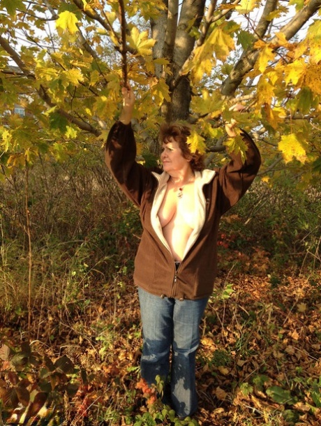 Under a tree, an older woman named Busty Bliss displays her big natural breasts.