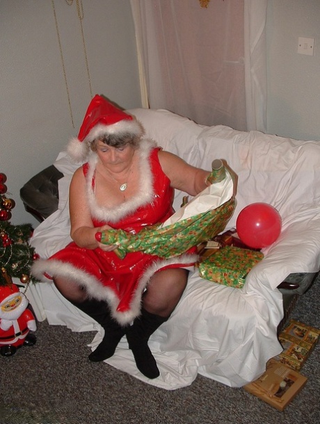 Obese mother Libby plays music while she cuddles with Santa on the covered couch.
