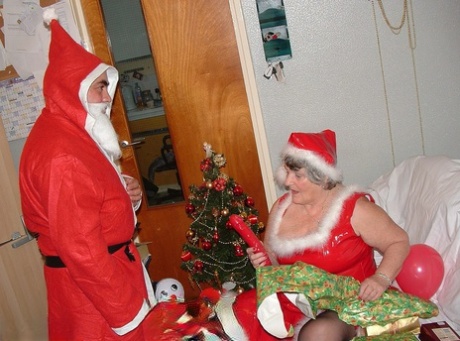 Grandma Libby, the elderly woman, enjoys cuddling up to Santa on a covered couch.