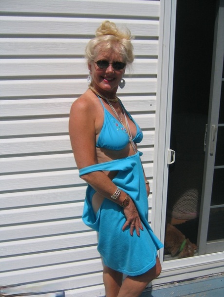Wearing a pair of sunglasses, Ruth, the mature blonde, releases her stomach and buttocks from a bikini.