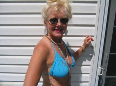 Using her sunglasses as protection, the adult blonde Ruth releases herself from a bikini and removes her breast tissue.