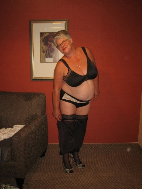 As the Girdle Goddess, an elderly woman with buff skinnies on her body, removes herself from clothes and wears stockings to release her excess.