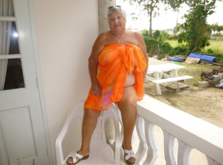 On a balcony, Grandmama Libby exposes her tan-worn body to the outside world.