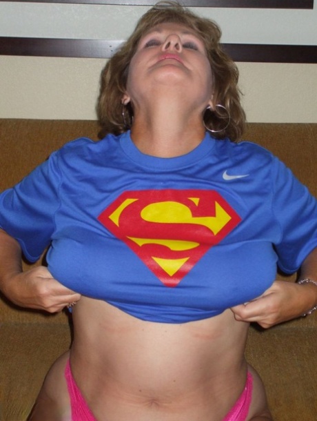 Adult Busty Bliss removes her significant hair from a Superman T-shirt.