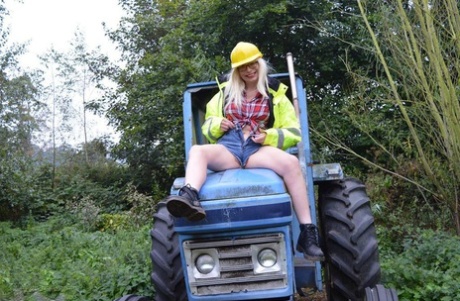 Young performer Barby Slut exposes herself on heavy equipment at a job site.