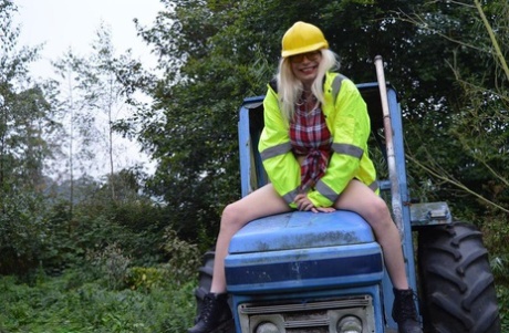 Barby Slut, a young performer, exposes herself on heavy equipment at a job site.