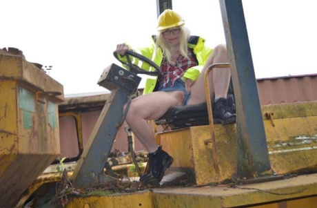 In an outdoor activity, Barby Slut bares herself on heavy equipment at a job site.