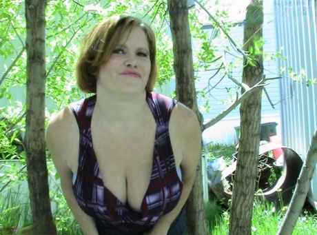 A thicker and older woman, Misha MILF, is seen exposing herself in a group of hardwood trees.