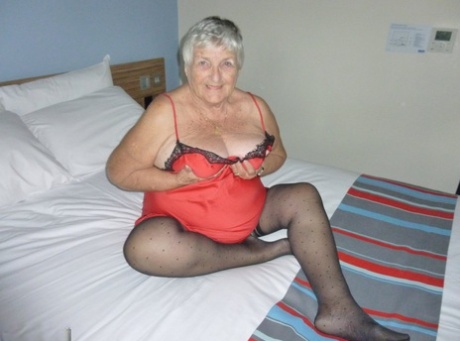 The obese Grandma Libby removes her lingerie before masturbating on the bed.
