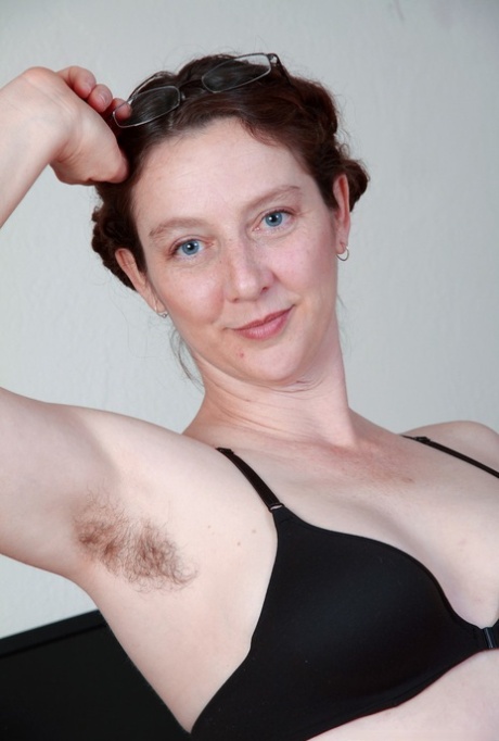 At home office, the solo model exposes her furry armpits and bush as she undresses.