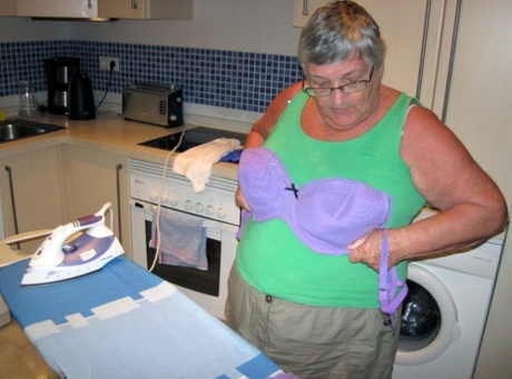 British oma, Grandma Libby, who is overweight, shows off her chest while ironing.