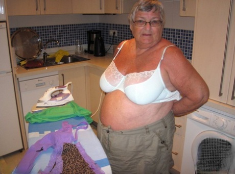 While ironing, Grandma Libby, an overweight British woman, displays her breasts.