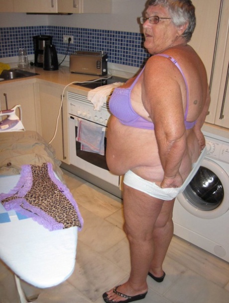 Grandma Libby, an overweight British woman, shows off her chest muscles while ironing.