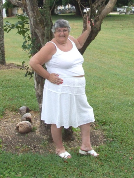 Grandma Libby, an obese British woman, exposes her large breasts beneath a tree.