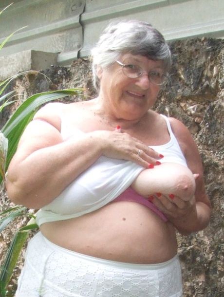 Grandma Libby, an elderly woman from Britain, exposes her sizable breasts beneath a tree.
