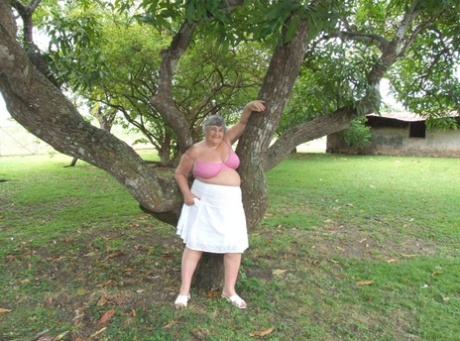 Old woman of British descent named Grandma Libby displays her huge breasts beneath a tree.