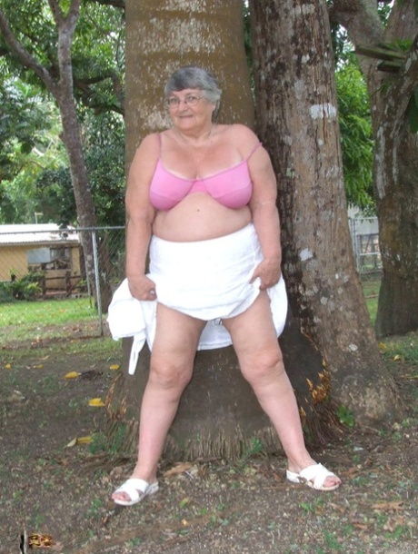 The elderly British woman, Grandma Libby, displays her sizable breasts beneath a tree.